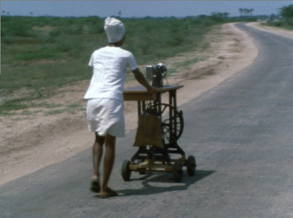 homme poussant une machine a coudre sur une route deserte en Inde